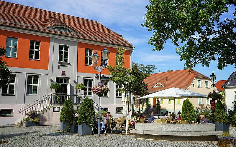 



    
        
                Marktplatz mit Restaurant Böfflamott,
            
        
                Foto: Tourismusverband Fläming e.V./Steven Hille
            
    
